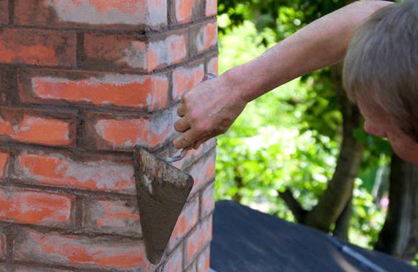 Trowel ruling fresh mortar joints along brickwork